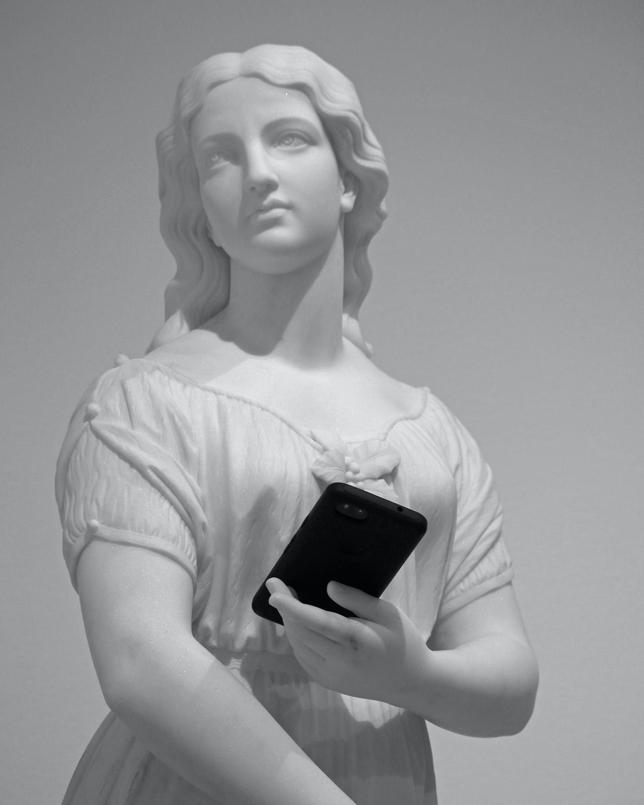 Statue d'une jeune femme tenant un téléphone portable