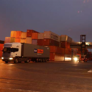 Photographie d'un camion au milieux de conteneurs sur un port