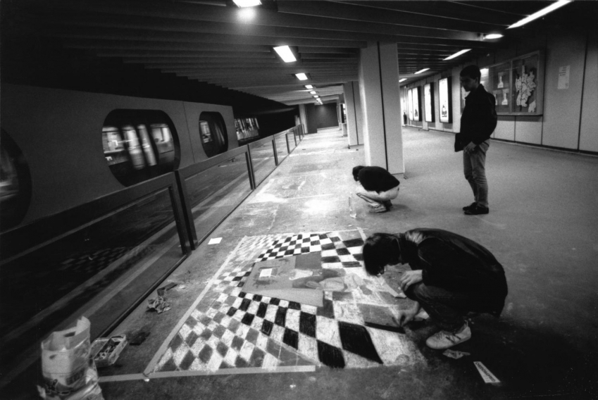 Photo d'artiste accroupi en train de dessiner à la craie sur le sol dans une station de métro