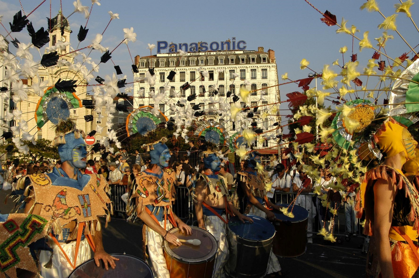 Photo d'un groupe de personnes en train de défiler avec des tambours et des coiffes aux visages colorés et en train de crier
